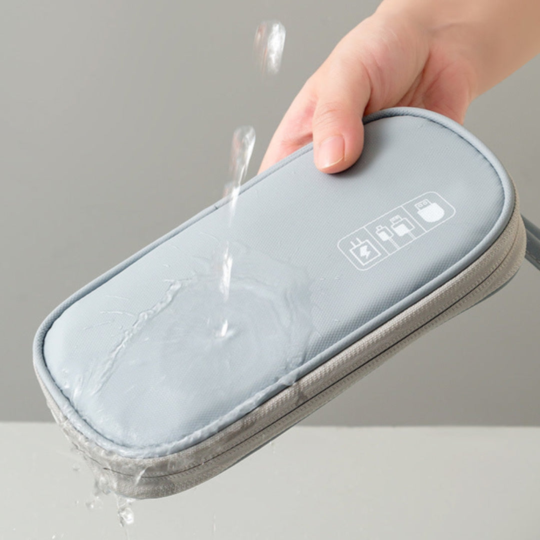 Hand holding a gray electronic device with water splashes on a gray background